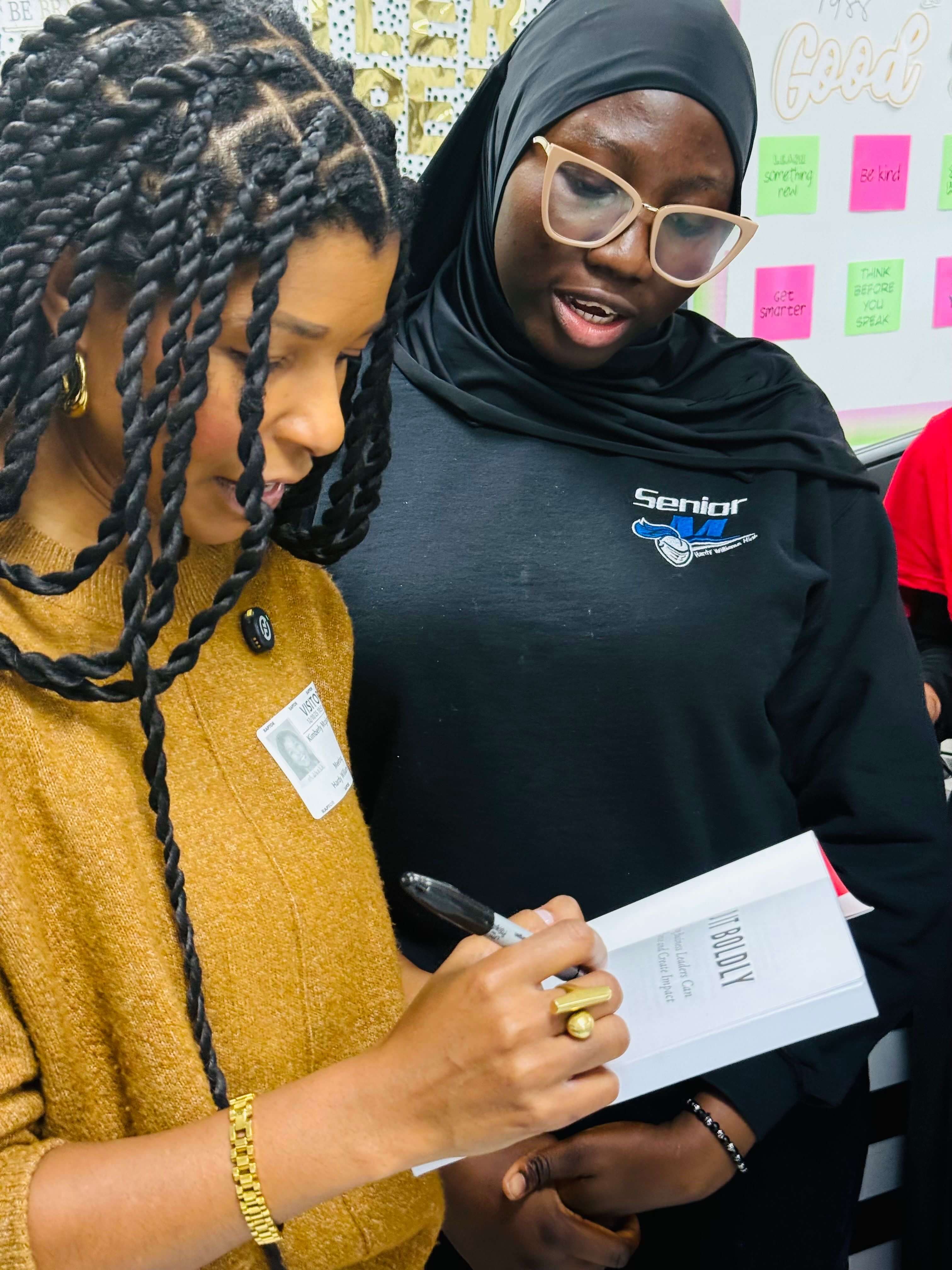 Build It Boldly facilitator signing a book for a student after a leadership and personal reflection workshop.