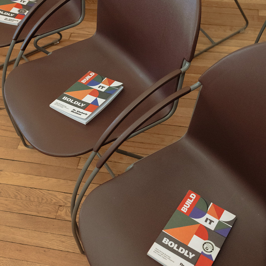 Copies of Build It Boldly by Dr. Kimberly McGlonn placed on chairs before an author talk or book event.