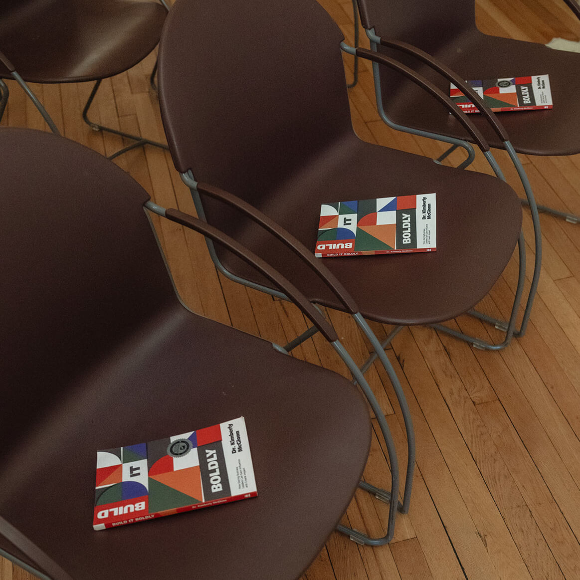 Copies of Build It Boldly by Dr. Kimberly McGlonn placed on chairs for a leadership event or book talk.