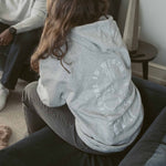 Back view of a heather gray Build It Boldly hoodie with boxing gloves graphic and “The Future Is Worth the Fight” design in a lifestyle setting.