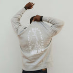 Back view of a man wearing a heather gray Build It Boldly sweatshirt with “The Future Is Worth the Fight” boxing gloves graphic.