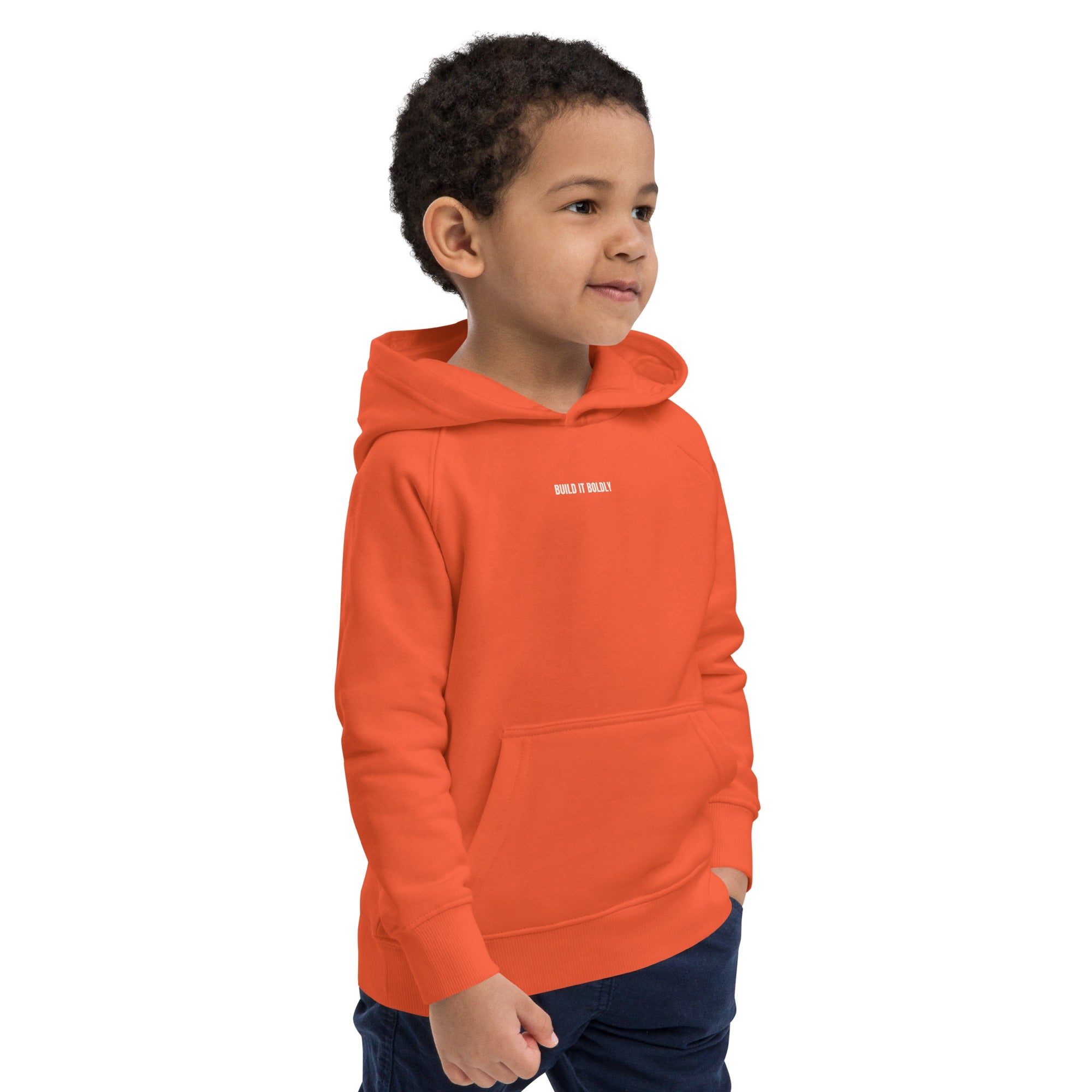 Child wearing a burnt orange Build It Boldly kids hoodie with small white chest logo, shown in right side view.