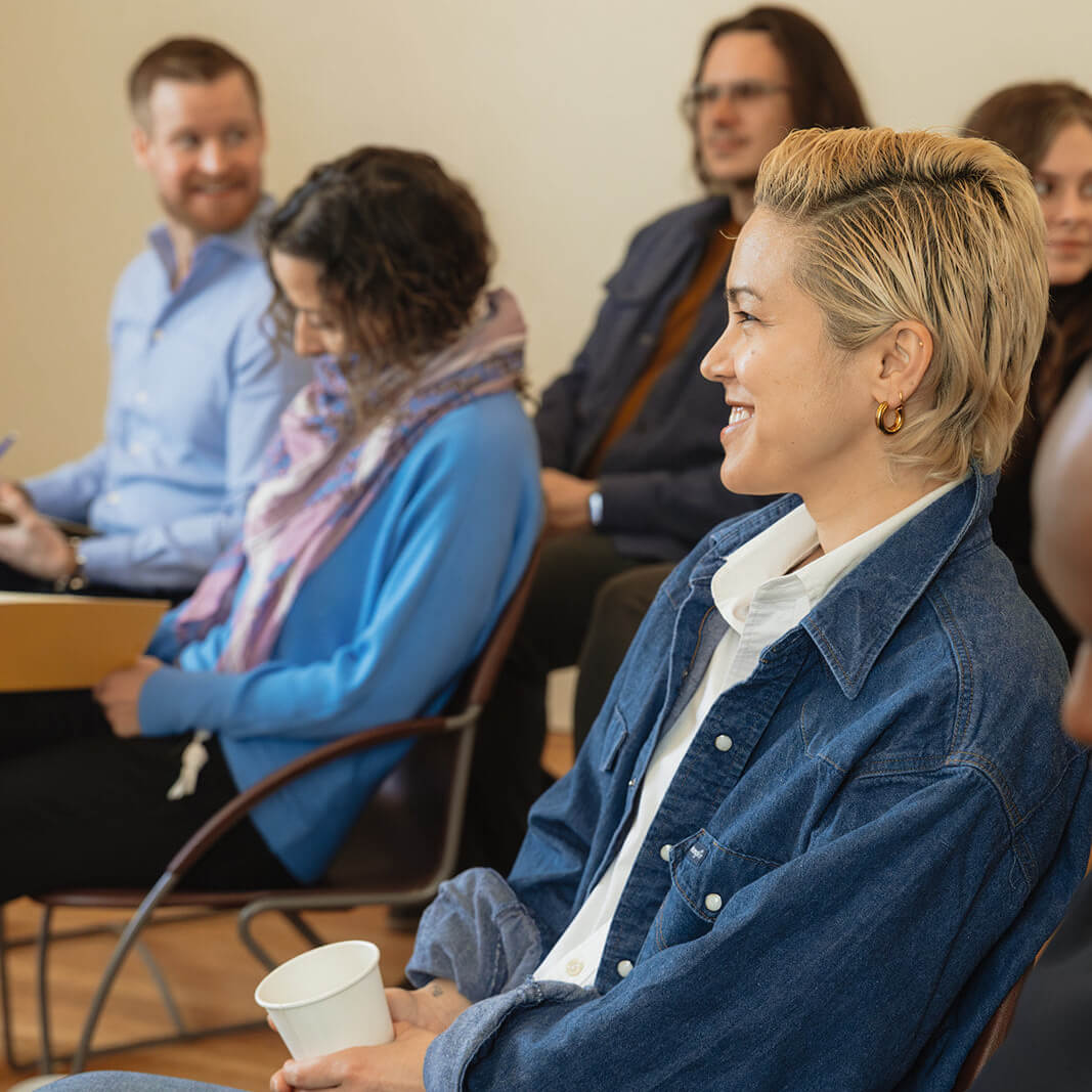 Workshop attendee smiling and listening during a Build It Boldly leadership session while holding a coffee cup.