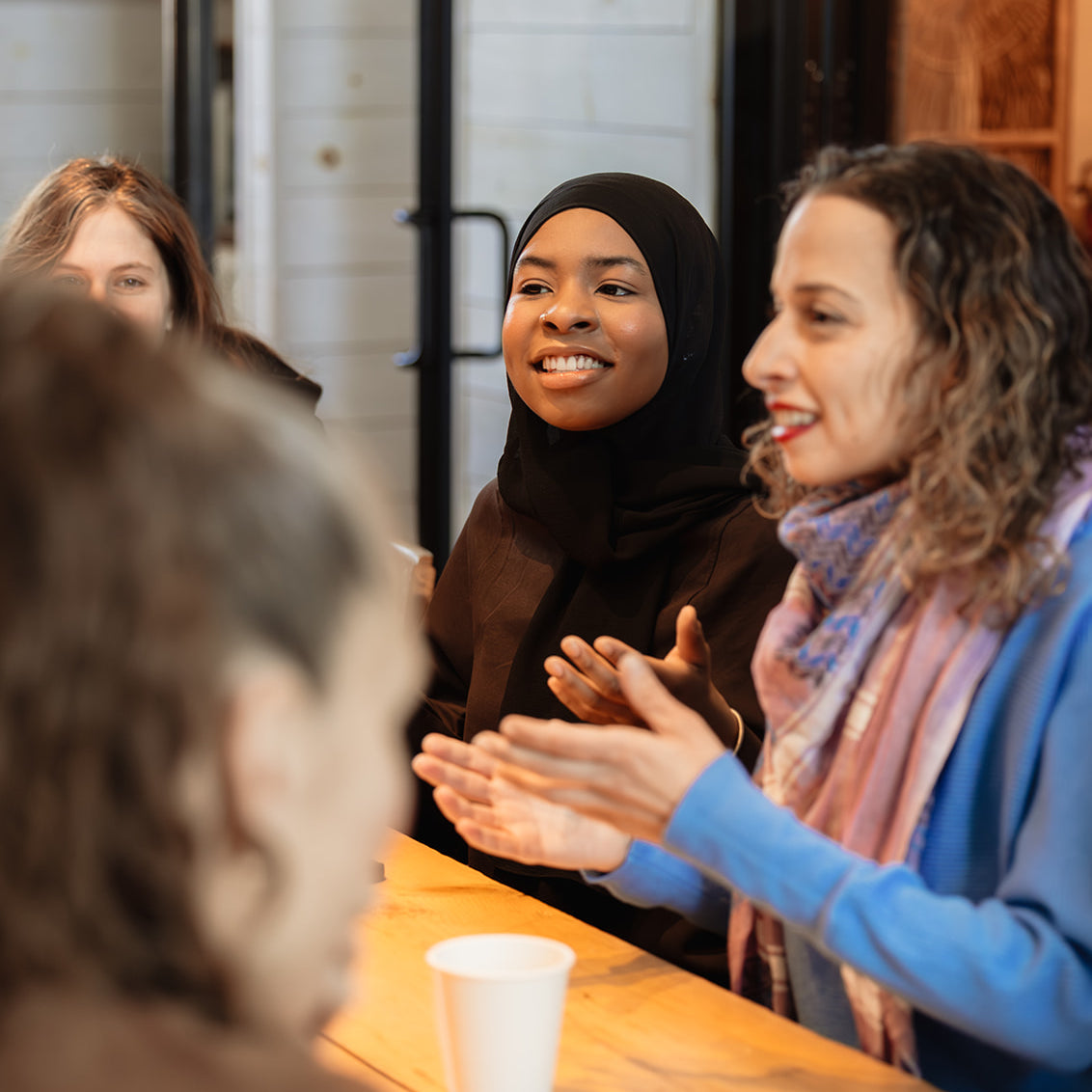 Diverse group of workshop participants in conversation around a table during a Build It Boldly leadership session.
