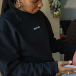 Close-up of Dr. Kimberly McGlonn wearing a black Build It Boldly sweatshirt while holding an open journal