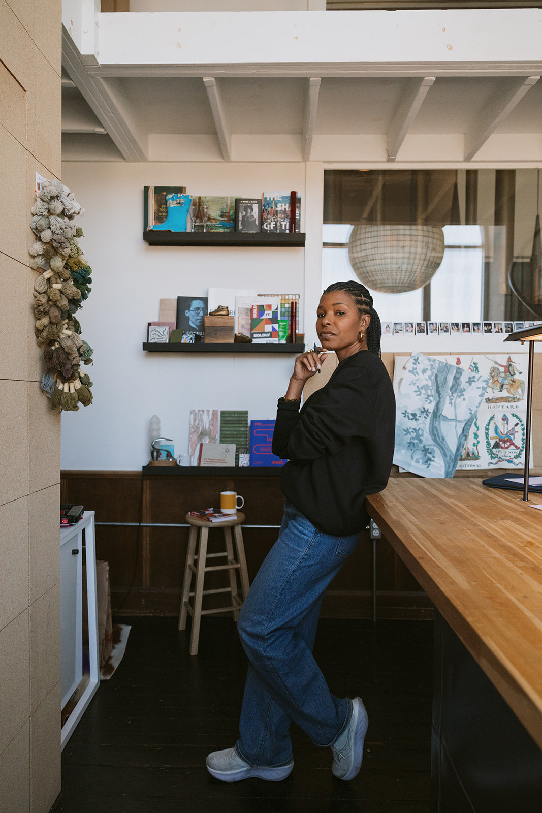 Dr. Kimberly McGlonn standing in a creative studio space beside a large worktable with books and artwork displayed behind her