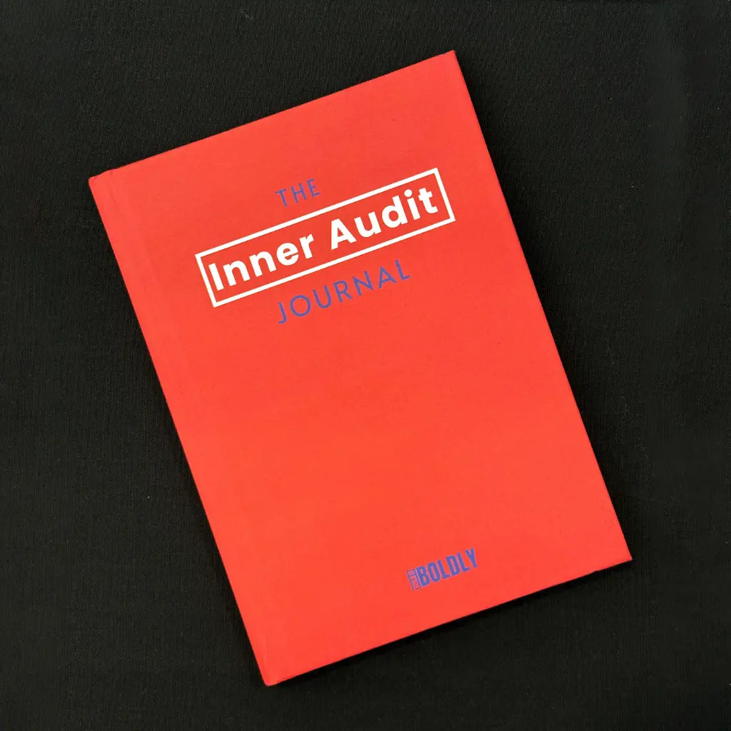 Front cover of The Inner Audit Journal by Build It Boldly on a dark surface, featuring a bold red-orange cover with minimalist typography.
