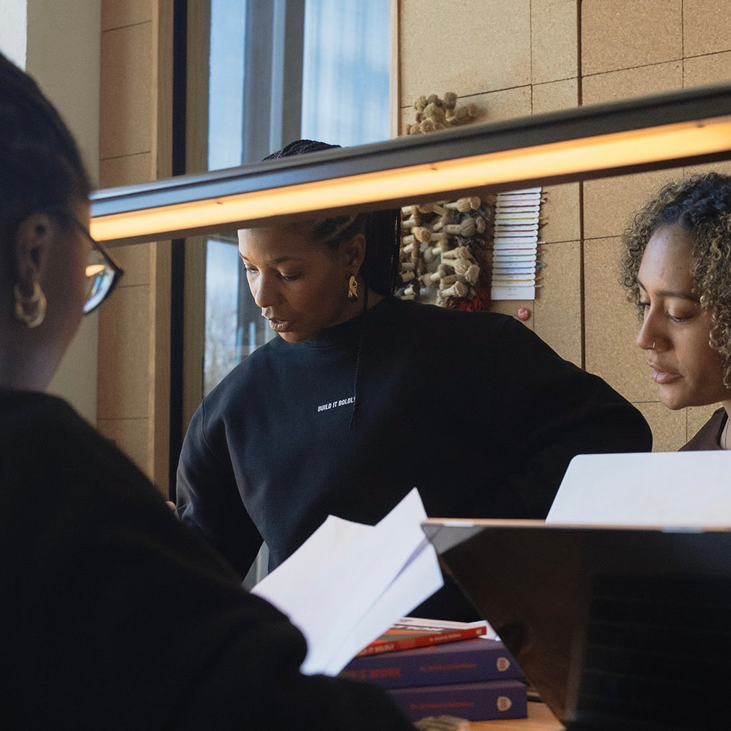 Diverse team collaborating at a table with books and laptops, focused on leadership development and intentional work